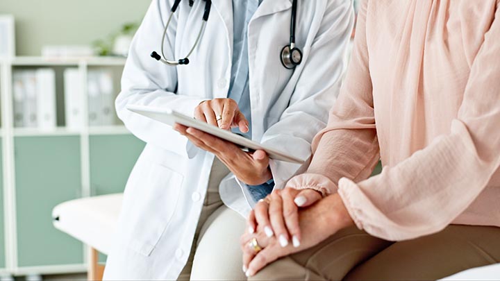 A doctor using a tablet to discuss test results with a patient.