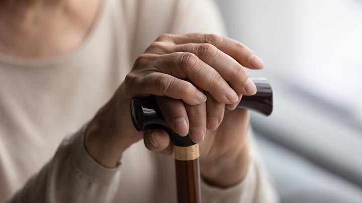 Hands resting on a walking stick.