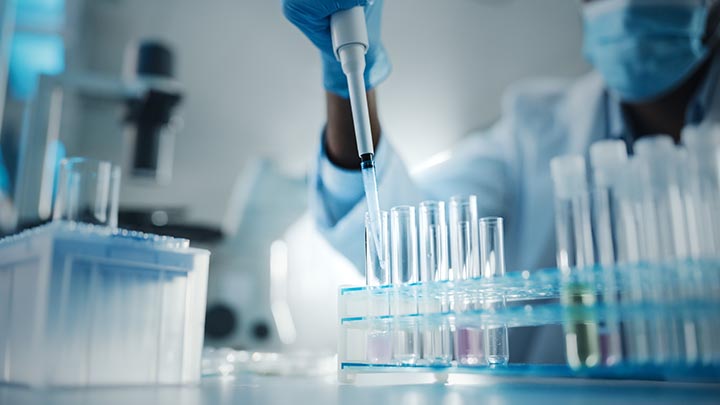 A researcher pipetting liquid into test tubes.